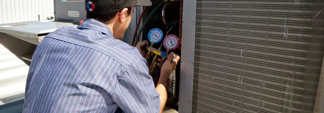 HVAC technician servicing a condenser unit in Farmville
